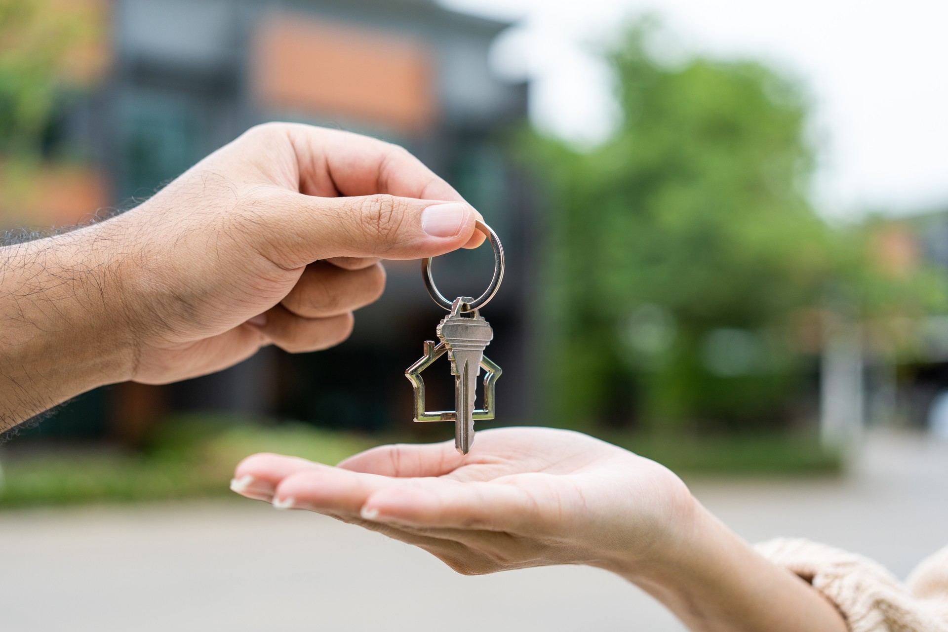 Femme achetant ou louant une nouvelle maison qu’elle tient clé devant la nouvelle maison. Surprise heureuse jeune femme asiatique donnant la clé de la maison et sourire pour louer ou acheter une maison d’appartement. Concept de déménagement de dém